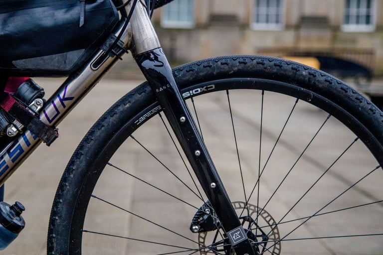 Black carbon Kinesis Range fork with cage mounts on the Tripster V3, fitted with a CX Disc wheel and gravel tyre.