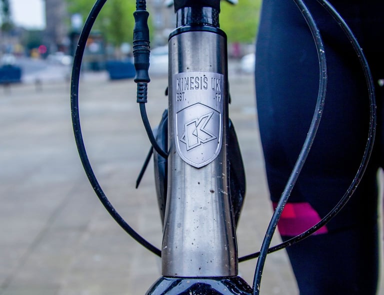 Kinesis UK Est. 99 badge on the Tripster V3 head tube, with the internally routed cables looping past it.