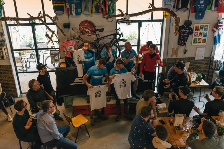 Riders in blue jerseys hold up white T-shirts at the prize giving in the Cyklist café after the Backyard Breakaway.