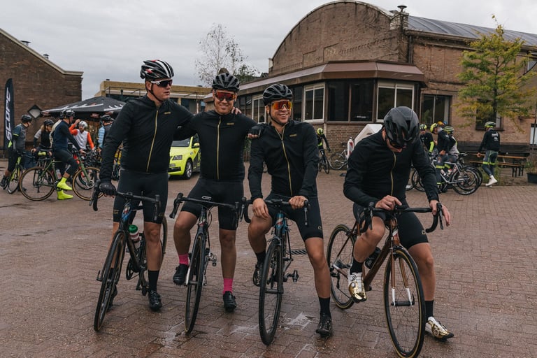 Four riders in black jackets pose on their bikes on a wet brick square before the Backyard Breakaway start.