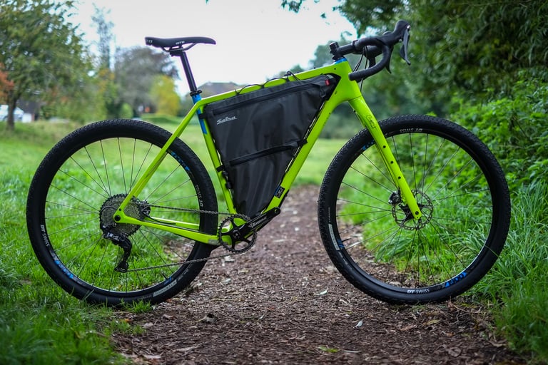Side view of the 2020 Salsa Cutthroat with its bolt-on frame bag fitted, parked on a path between grass.