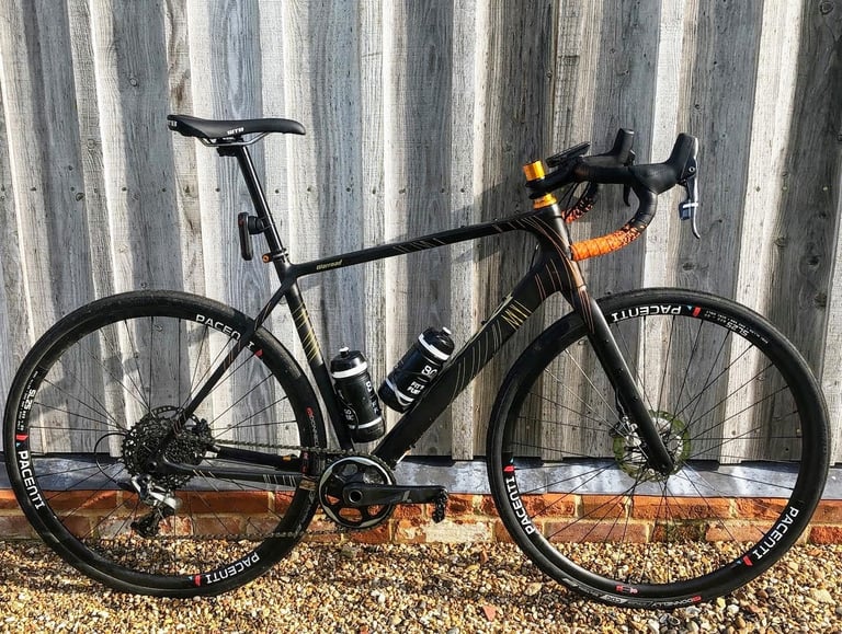 Salsa Warroad fitted with 700c slick tyres and Pacenti wheels, leaning against a timber-clad wall.