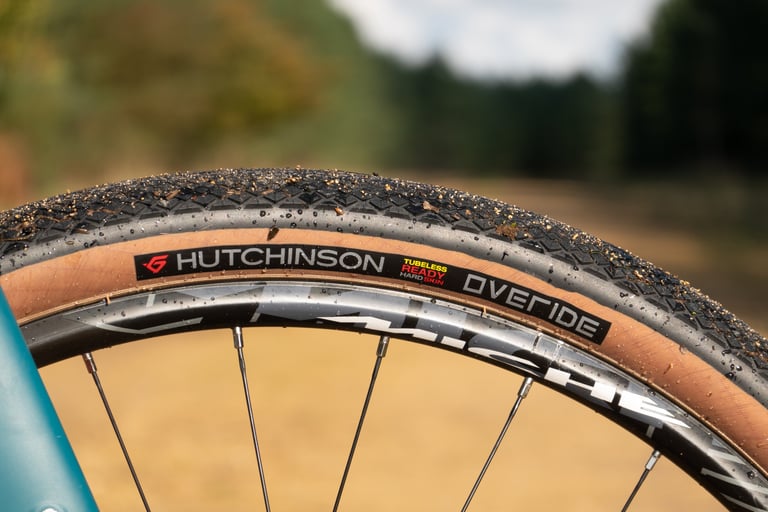 Hutchinson Overide 650b sidewall with its Tubeless Ready Hard Skin label, wet and gritty on a forest track.