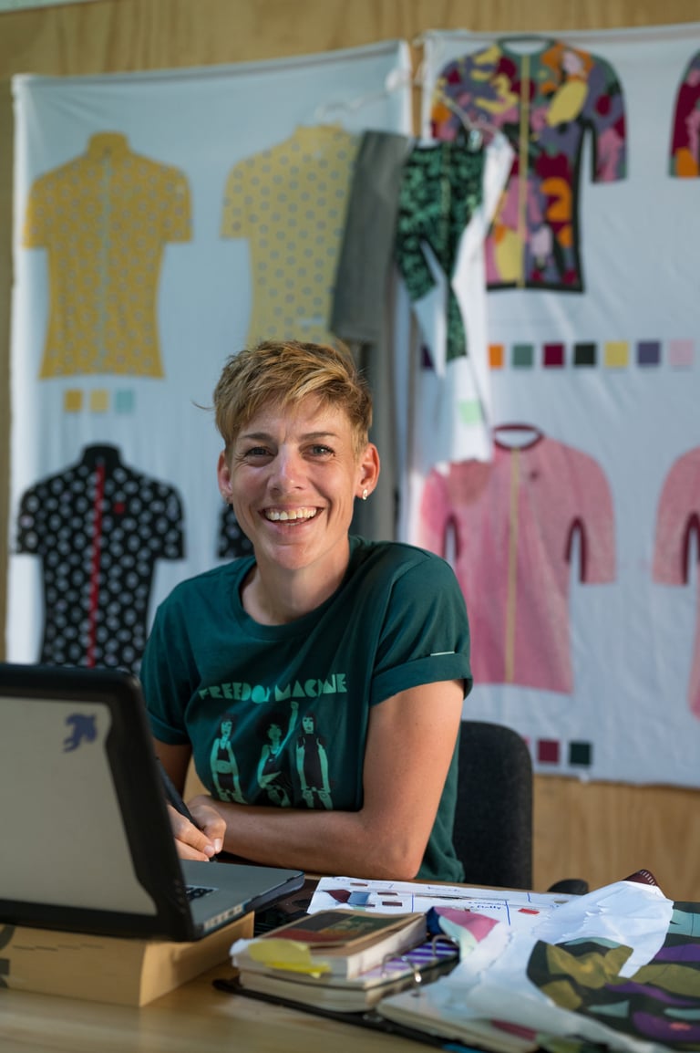 Iris Slappendel, founder of IRIS, smiles at her desk in Rotterdam with jersey designs on the wall behind her.