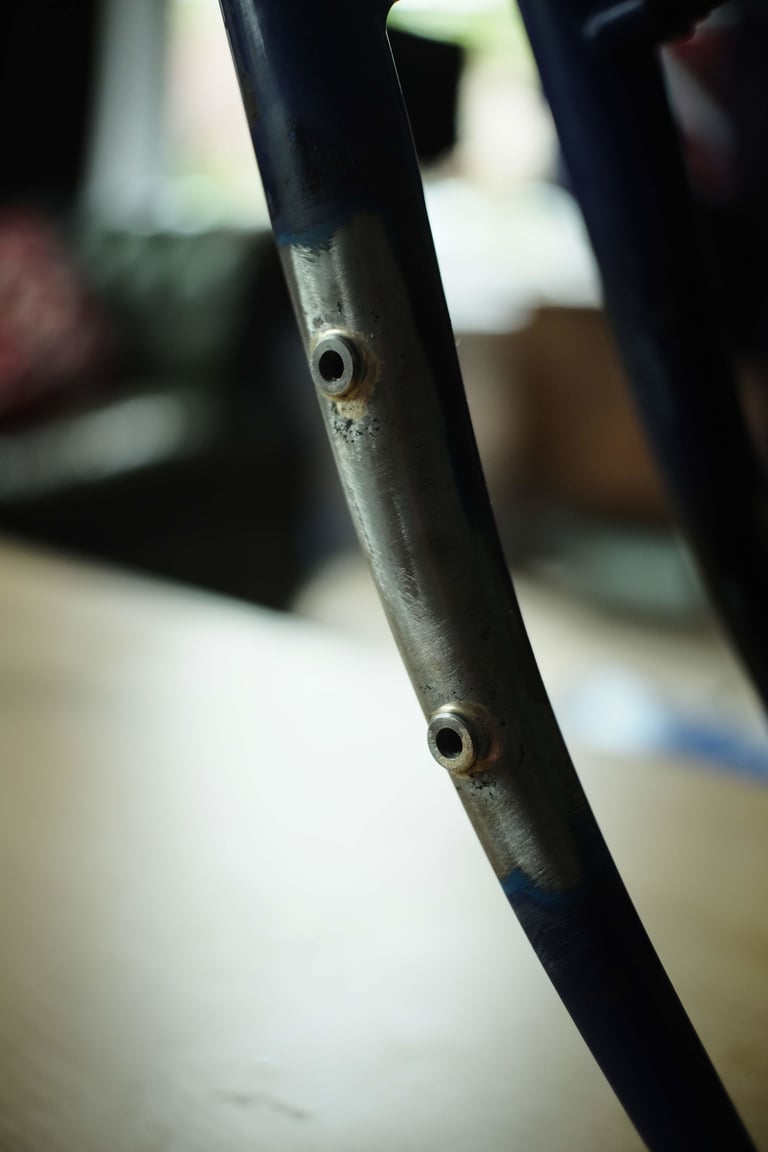 Two brazed-on bosses on a bare steel fork leg of an old MTB, added for extra bottle cages and luggage.