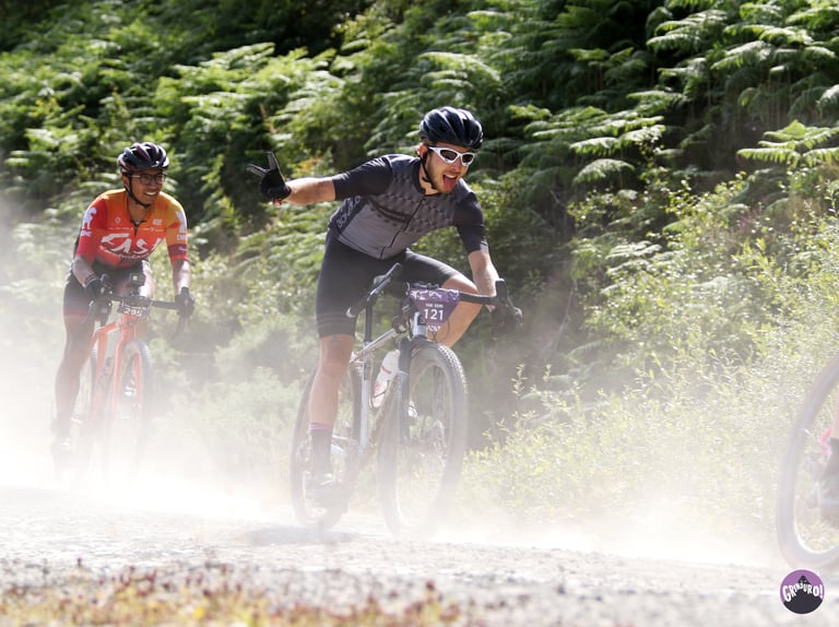 Two riders kick up dust on a forest gravel track during a Grinduro race, ahead of the 2020 move to Wales.