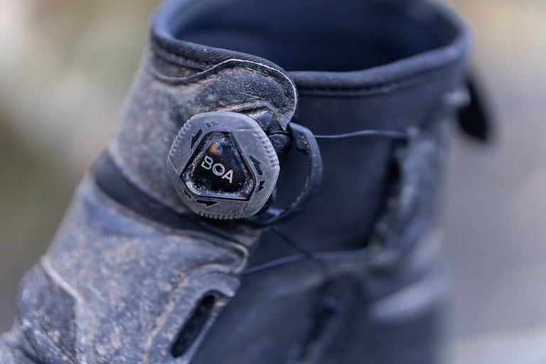 Close-up of the BOA lacing dial on a muddy Lake MX145 winter boot.
