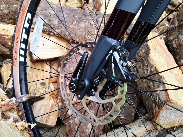 Front thru-axle ratchet skewer and Shimano 105 flat-mount disc brake caliper on the Pinnacle Arkose D3 fork.