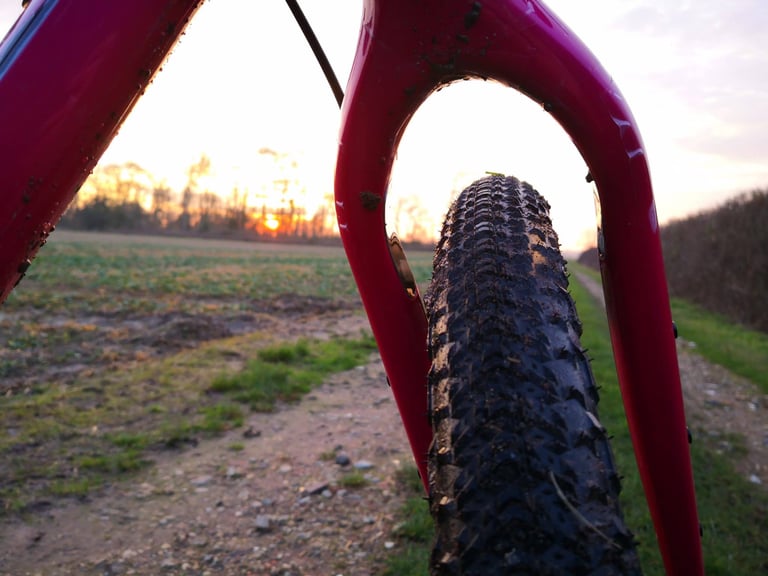 Salsa Cutthroat fork legs framing a Teravail Sparwood front tyre, showing generous mud clearance at sunset.