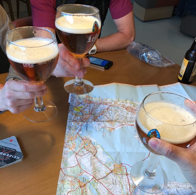 Three glasses of beer raised over a folded paper road map of the Amsterdam area on a table.