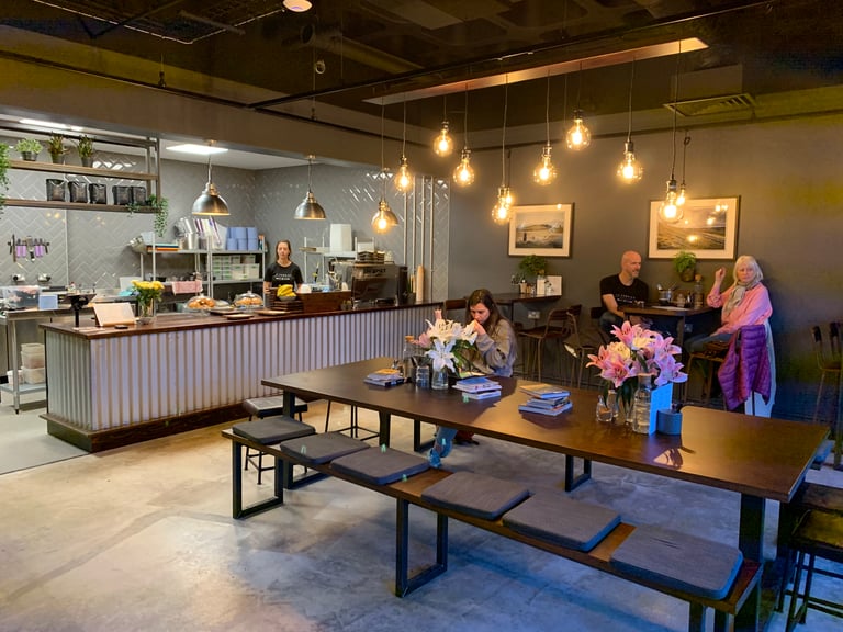 La Fabrica cafe inside The Service Course Wilmslow, with a long table, pendant bulbs and a corrugated-front counter.