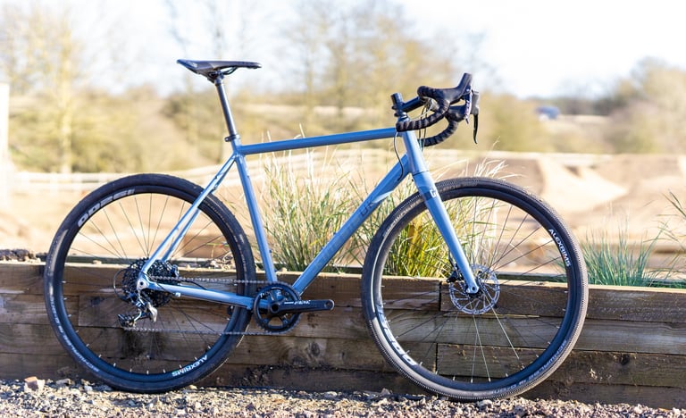 Kinesis G2 all-road bike in slate blue, side view, with SRAM Apex 1x drivetrain and Schwalbe G-One tyres.