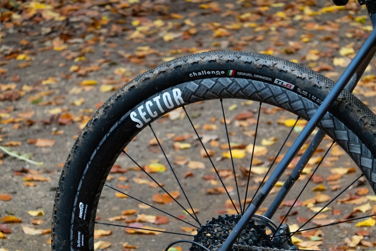 Rear Sector GCi wheel with a muddy Challenge Gravel Grinder 42mm tyre looking full and rounded on the wide rim.