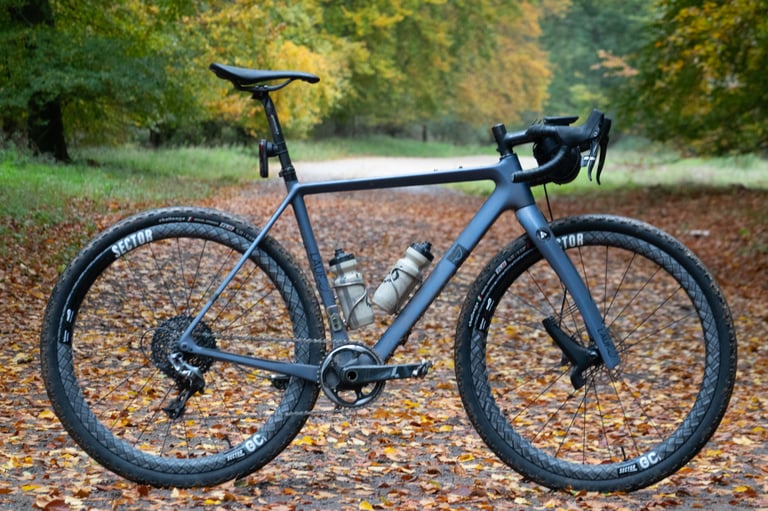 Lauf True Grit on Sector GCi wheels, side view on a leaf-covered track through autumn woodland.