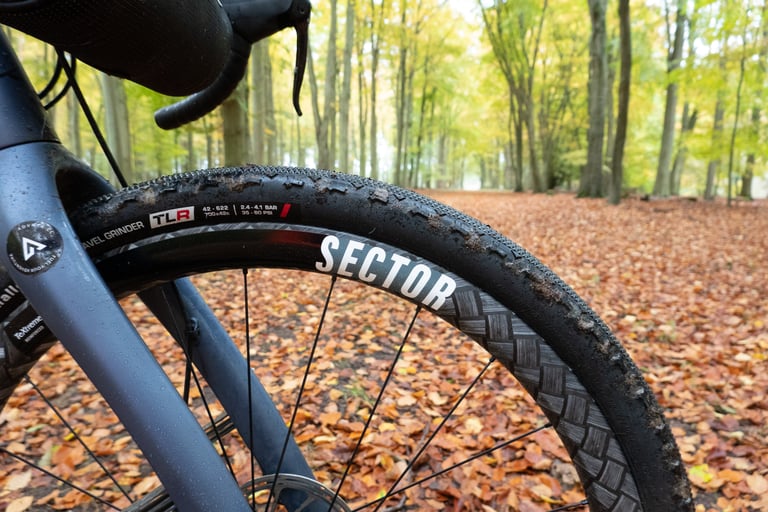 Front Sector GCi wheel with a 42mm Challenge Gravel Grinder tubeless tyre, on a woodland track of fallen leaves.