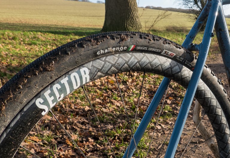 Mud-caked Challenge Gravel Grinder tubeless tyre on a Sector rim, with the CushCore insert hidden inside.