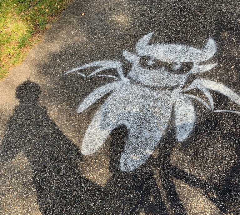 White stencilled winged devil painted on tarmac, road graffiti from the Further race route in France.