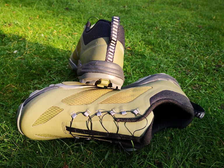 Shimano MT-7 shoes on grass, showing the BOA lacing, mesh upper and rear pull tab, with one lying on its side.