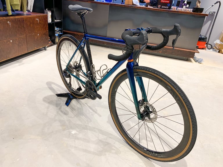 Isen gravel bike with a blue-green colour-shift frame and tan-wall tyres on display in The Service Course Wilmslow.