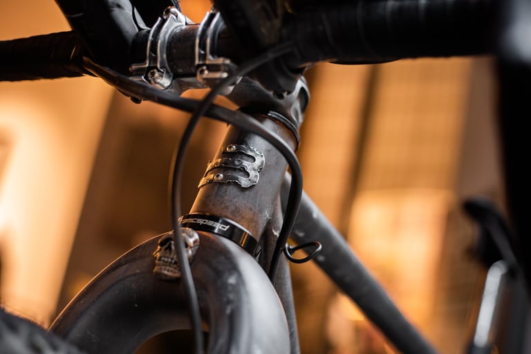 Close-up of the Belle Cycles A.T.E.R. weathered head tube with its metal badge and skull emblem on the fork crown.