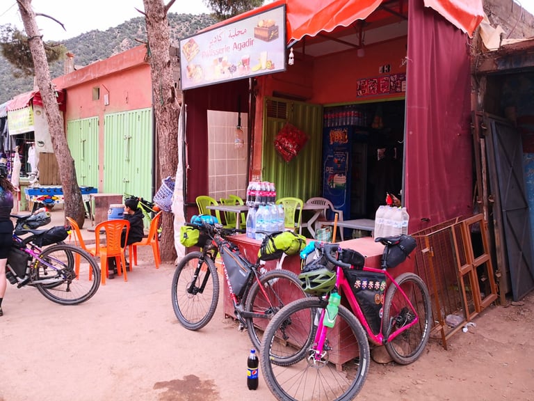 Loaded bikes parked outside a small roadside shop and pâtisserie on day one of the Atlas Mountain Race in Morocco.