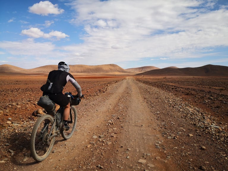 Benny Simpson rides a loaded hardtail mountain bike along a stony desert track during the Atlas Mountain Race in Morocco.