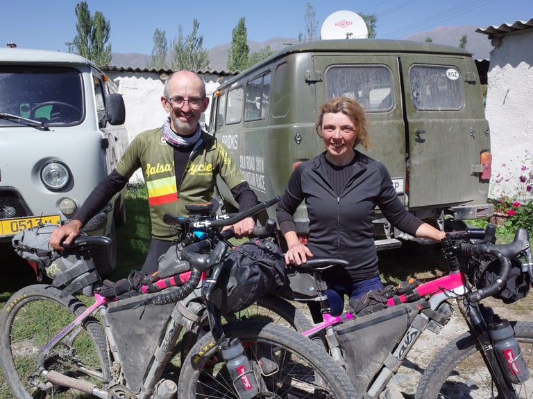 Shona and Rich of Keep Pedalling with their pink Salsa Cutthroats beside a Silk Road Mountain Race van in Kyrgyzstan.