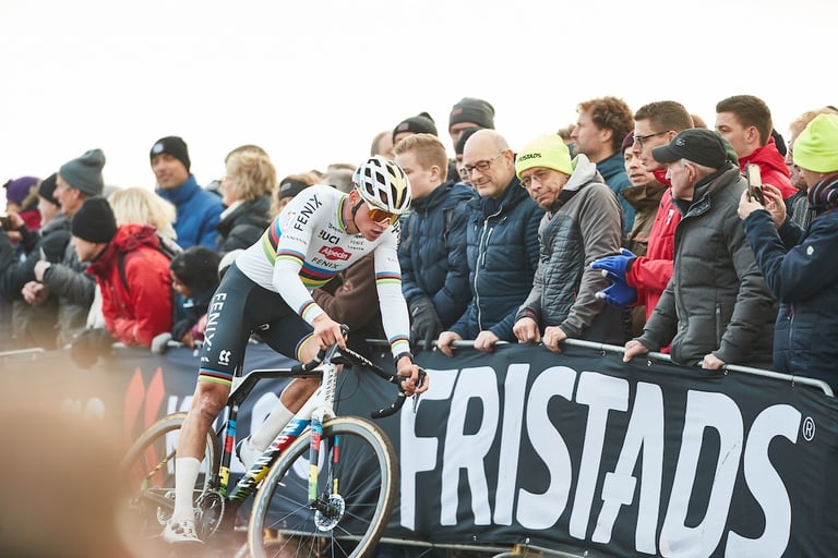 Mathieu van der Poel in the rainbow jersey rides past a Fristads banner and fans at Hoogerheide.
