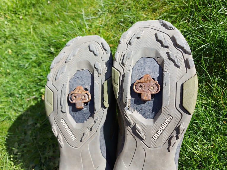 Soles of the Shimano MT-7 shoes after the Atlas Mountain Race, with chunks missing from the lugs and rusty SPD cleats.