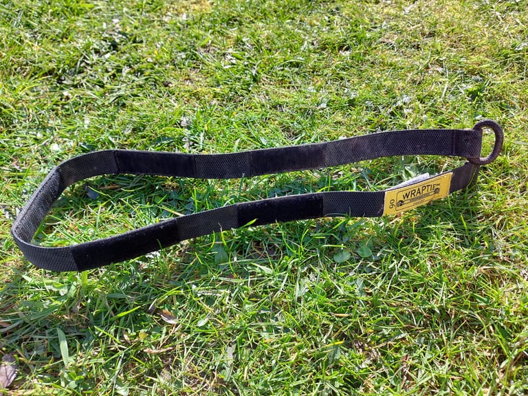 Wraptie 90cm tie-down strap with velcro sections and a yellow label, laid out on grass.