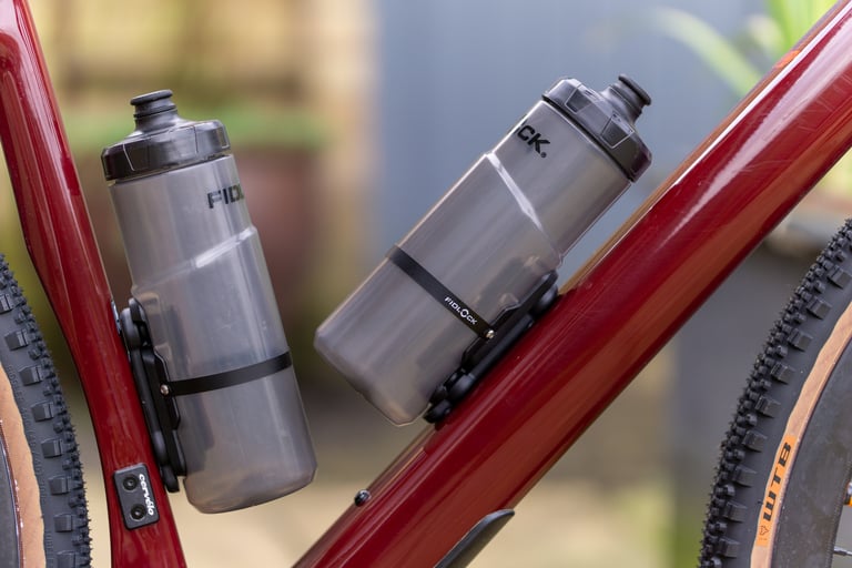 Two Fidlock TWIST bottles mounted on the seat tube and down tube of a red gravel bike with tan-wall tyres.