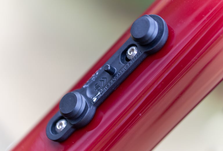 Close-up of the minimal Fidlock TWIST frame mount, held on a red frame by two low-profile Allen screws.