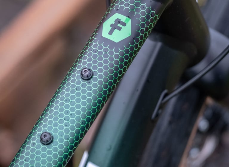 Two top tube bag mounts and the F logo on a green FUSTLE Causeway GR1 tube with a rain-beaded hexagon graphic.