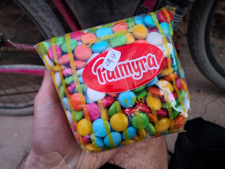 Hand holds a 1kg bag of colourful Palmyra sweets bought at the Aguinane checkpoint shop on the Atlas Mountain Race.
