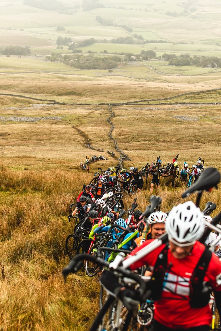 Riders shoulder their bikes in a long line up Simons Fell during the 3 Peaks Cyclocross 2019.