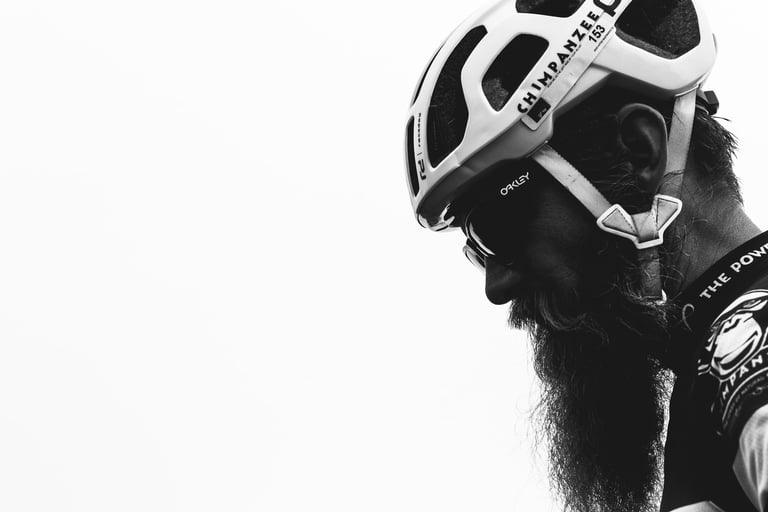 Black and white profile portrait of Ondrej of Chimpanzee Nutrition, long beard below a white helmet and Oakley glasses.