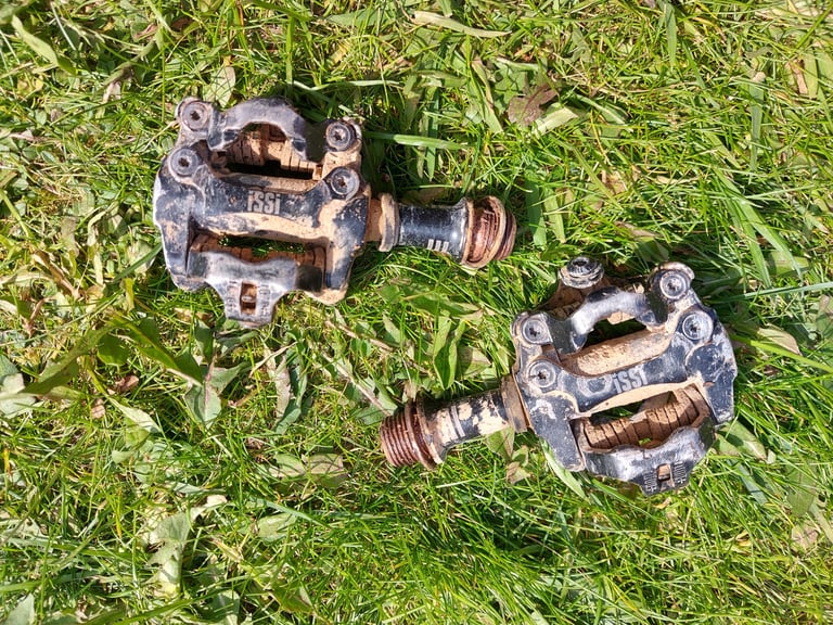 Pair of iSSi II Triple pedals lying on grass, caked in dirt and dust after the Atlas Mountain Race in Morocco.