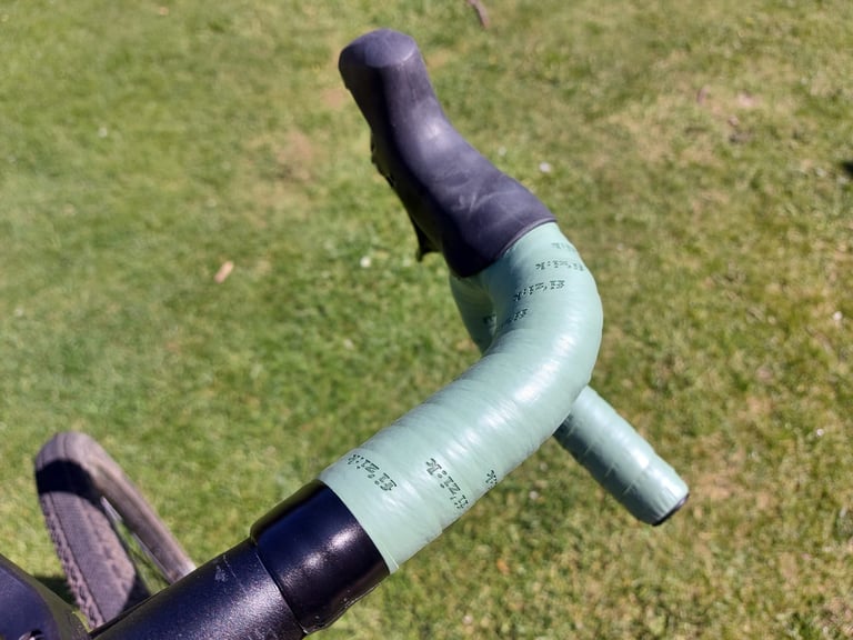 Fizik Terra tape in green-blue wrapped on a gravel bike drop bar, with printed logos along the wraps.
