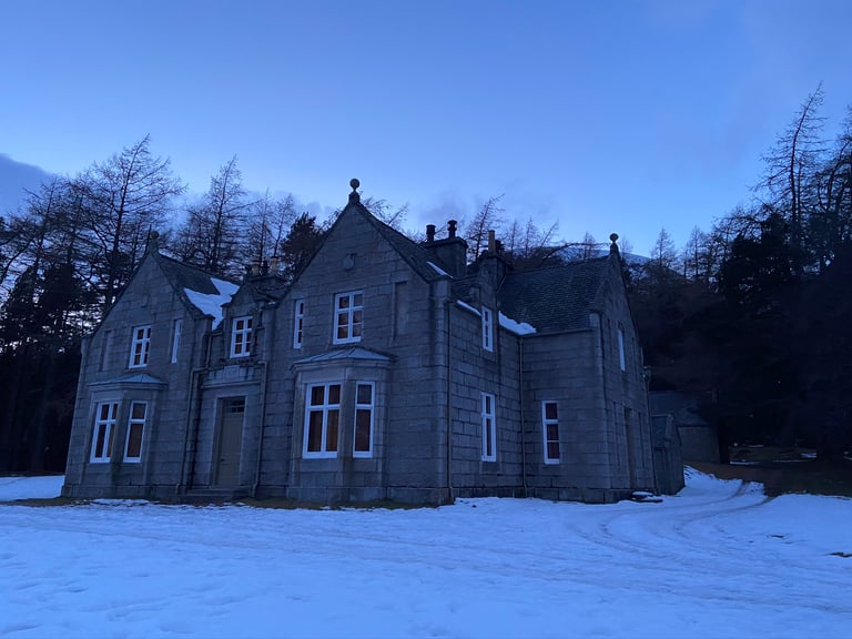 Glas Allt Shiel, Queen Victoria's granite lodge, at dusk with snow on the ground near Loch Muick.