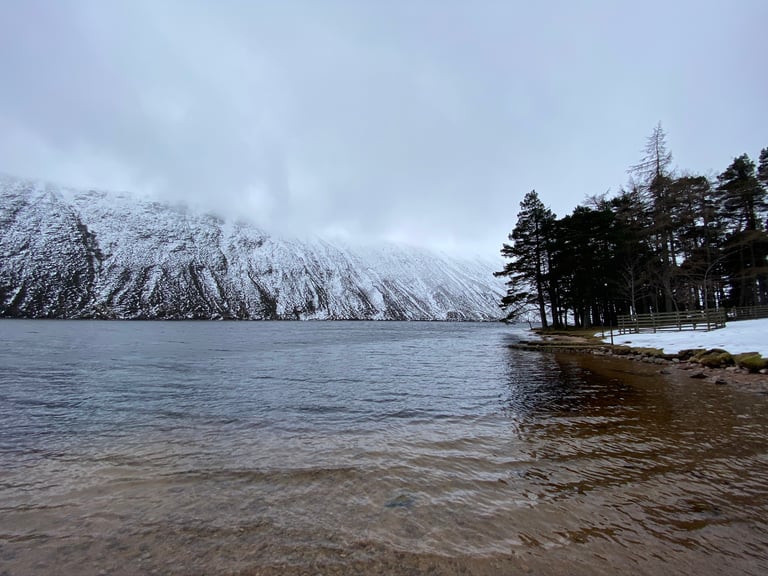 Cairngorms loch shore with snow-covered slopes vanishing into low cloud on day two of the ride.