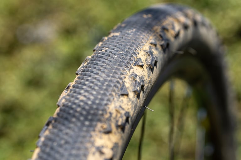 Close-up of the Challenge Gravel Grinder's fine file tread and large side lugs, dusted with dry mud.