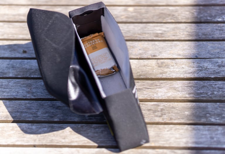 Slim interior of the Apidura Racing top tube bag, open on wooden decking with a single snack bar inside.
