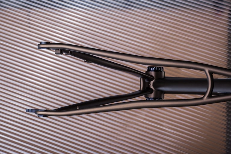 Verne frame in the bronze paint option, rear triangle with seat stays and chainstays on a ribbed backdrop.