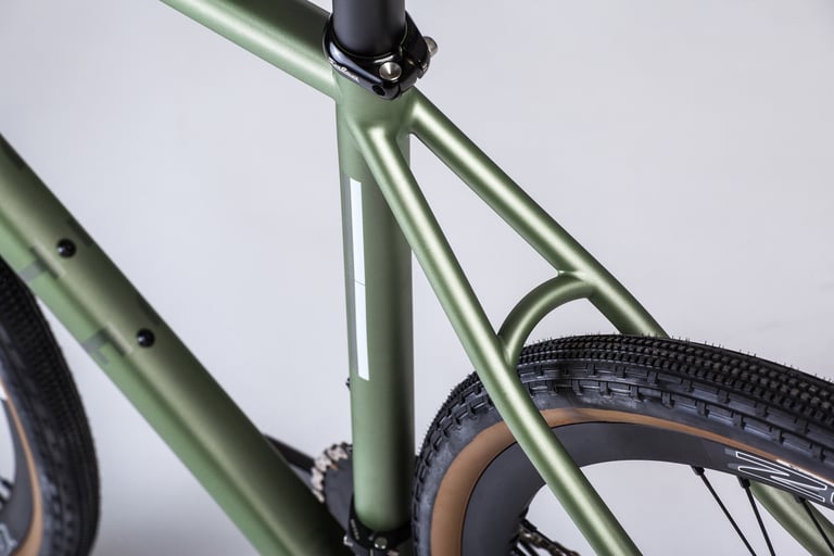 Close-up of the Verne's seat stays and seat tube junction, with tyre clearance visible, in matt green.