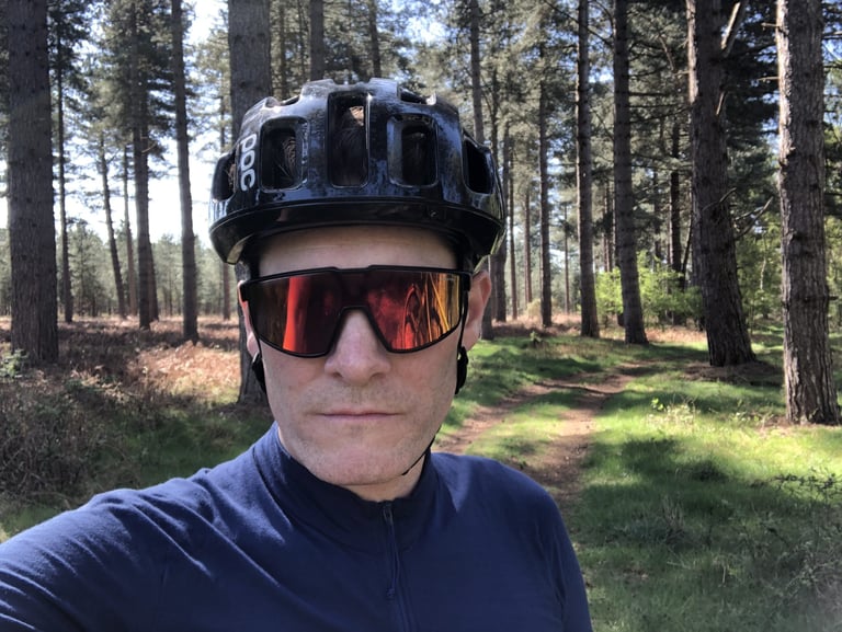 Rider wearing Julbo Fury Reactiv sunglasses and a black helmet on a forest trail, facing the camera.