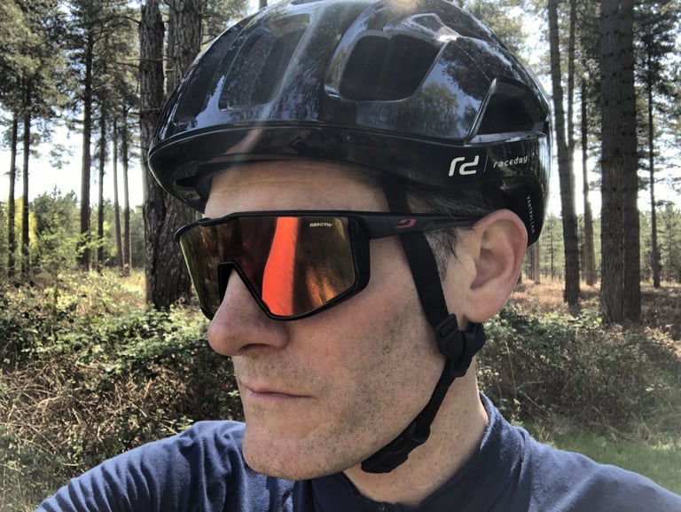 Side view of Julbo Fury Reactiv sunglasses worn under a helmet, showing the wide lens and slim arm.