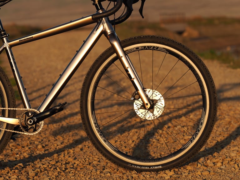Front half of the gold Salsa Stormchaser with Halo Carbaura wheel and Surly Knard tyre in warm evening light.