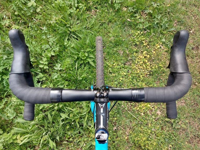 Rider's view down onto Driser 4-10 bars over grass, showing the slight flare of the drops and the raised flat tops.