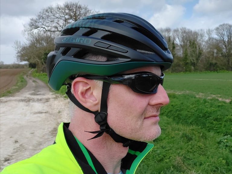 Reviewer in the Giro Agilis helmet and dark sunglasses, side profile, beside a chalky farm track and green field.