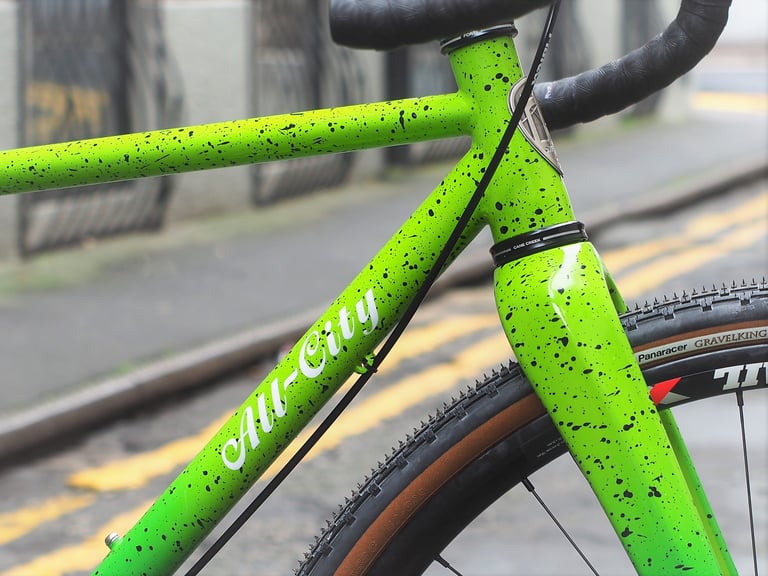 All City script logo on the down tube of the green Nature Boy, beside a Panaracer GravelKing tyre.